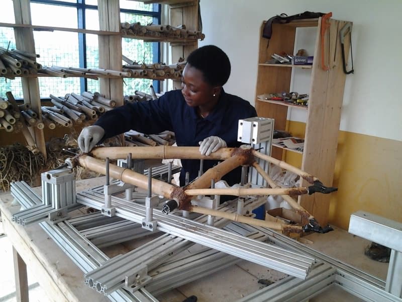 Winnifred Selby tightening a bamboo bike frame on a bench device.