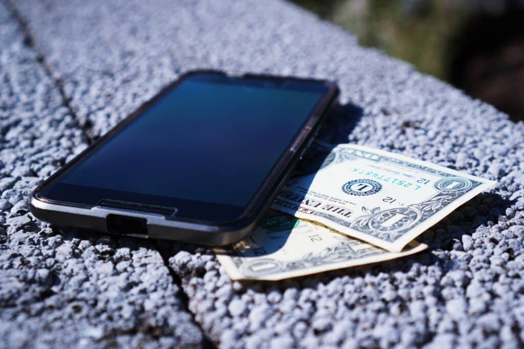 Smartphone resting on dollar bill cash