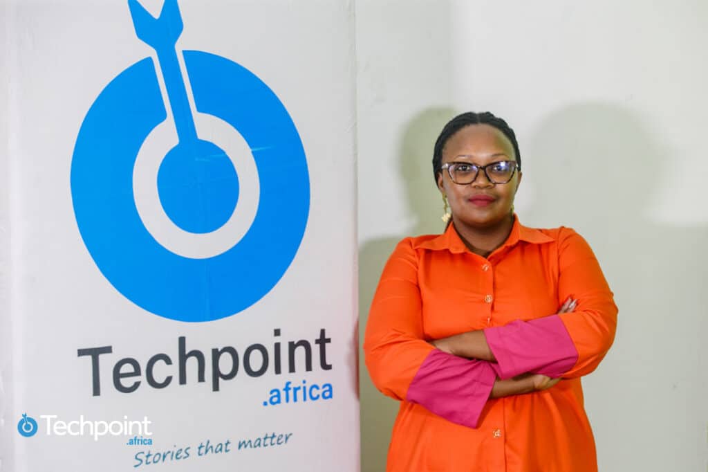 Brenda Wangari posing beside a Techpoint Africa Logo