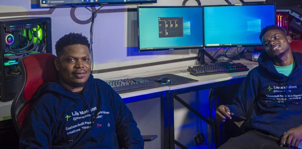 Debusayo Ayibiowu and Enitan Giwa sitting next to computer setups