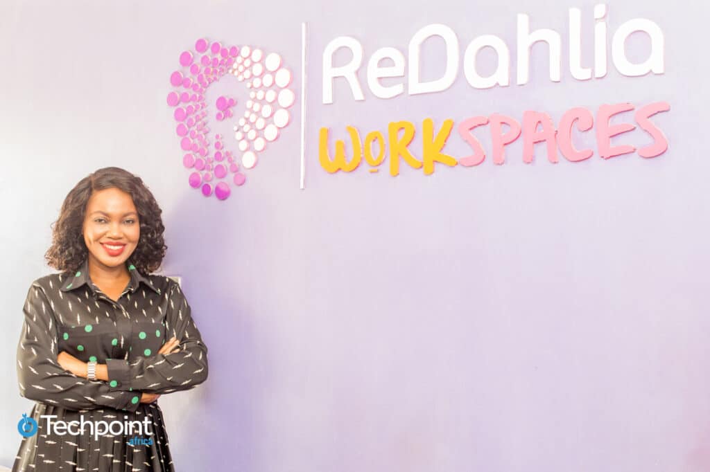 A picture of Florence Chikezie, standing beside a wall with Redahlia workspaces written on it