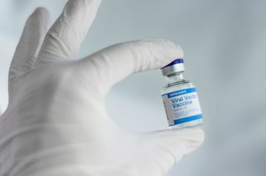 A hand holding a vaccine manufactured in the lab