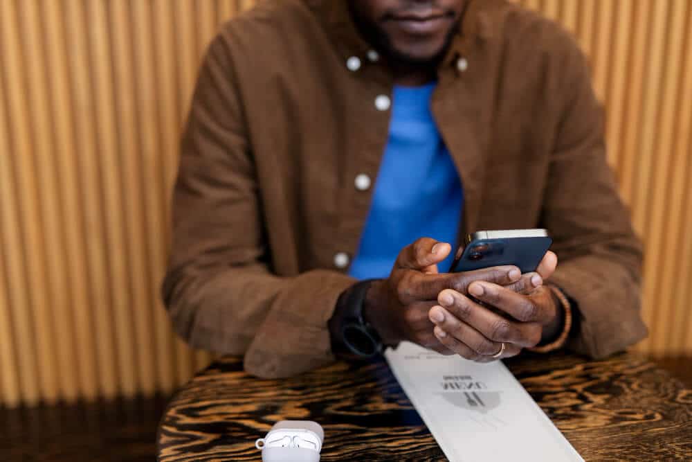 A picture of a man sitting in a restaurant holding is phone.