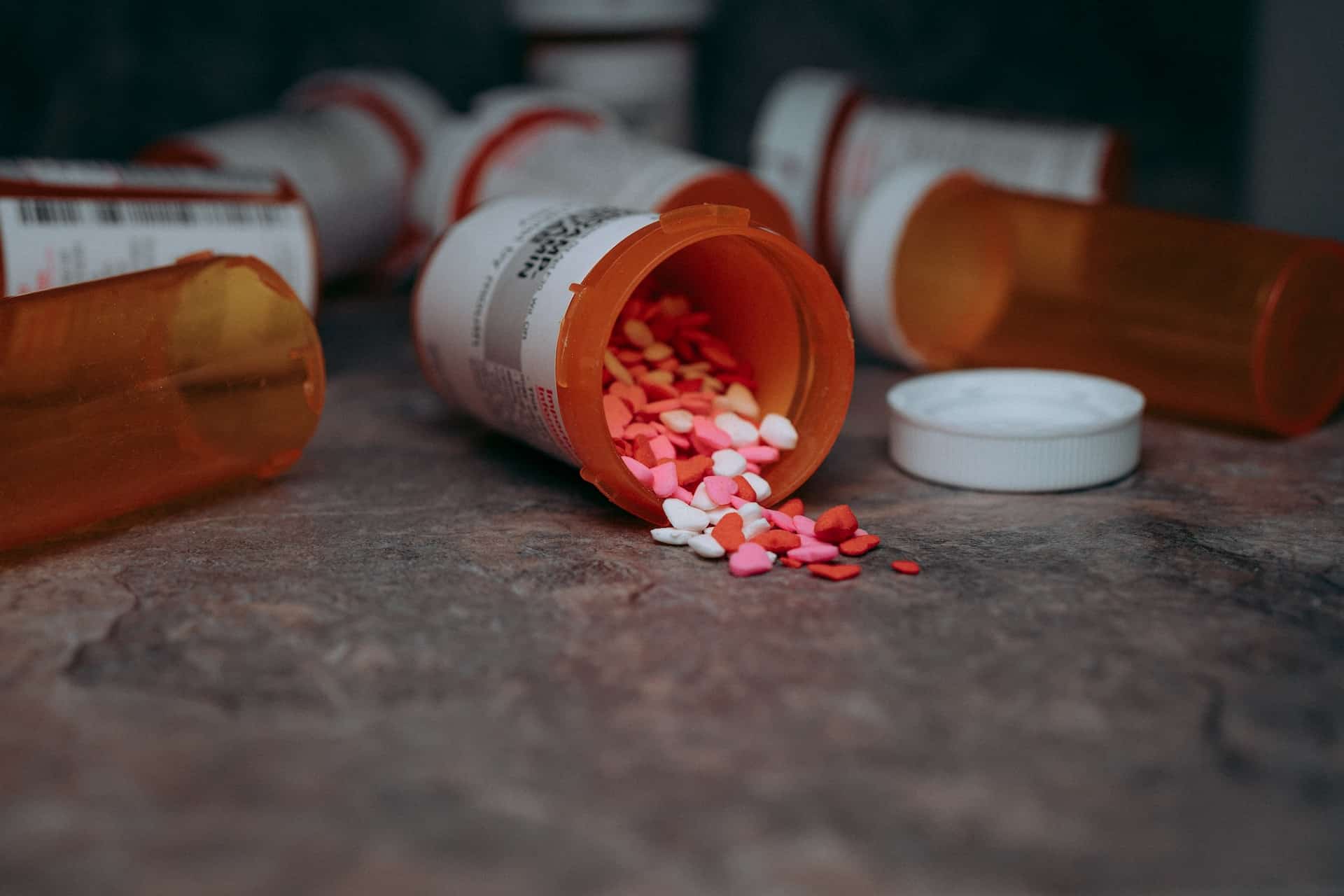 Several bottled drugs are on the floor, one of which is open and contains many medications