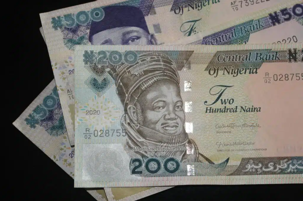 A close-up image of one old 200 naira note and two 500 naira notes on a plain balck background.